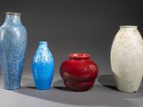 quatre vases de couleurs différentes sont alignés sur une surface grise