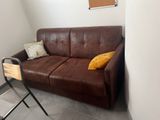 a brown leather couch sitting in a corner of a room