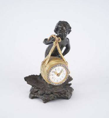 a small statue of a boy holding a clock on a branch