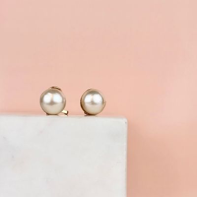 a pair of pearl earrings sitting on top of a marble block