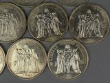 six different types of silver coins on a gray surface