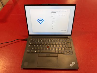 a laptop computer sitting on a red table with a wifi sign on the screen