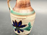 a brown and blue vase with a flower on it