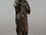 bronze statue of a woman holding a bird on a pedestal