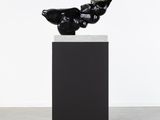 une sculpture noire représentant un oiseau perché sur un socle noir