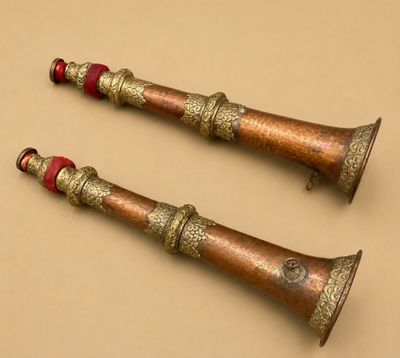 paire de clochettes anciennes en laiton ornées de perles rouges sur fond beige