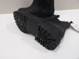 pair of black boots on a white table next to a white wall