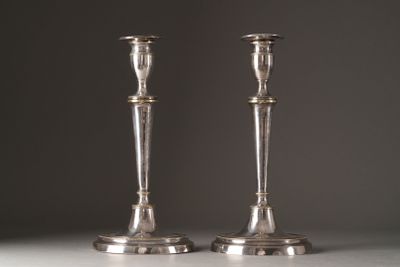 pair of silver candlesticks on a table against a grey background