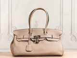 a beige leather handbag sitting on top of a wooden table
