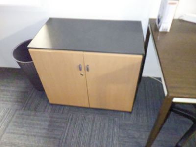 une petite armoire placée à côté d'un bureau dans un bureau