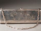 a silver purse with a chain around it on a table
