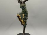 statue d'une femme en robe verte posée sur un socle noir
