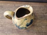 a small yellow and blue vase on a wooden table