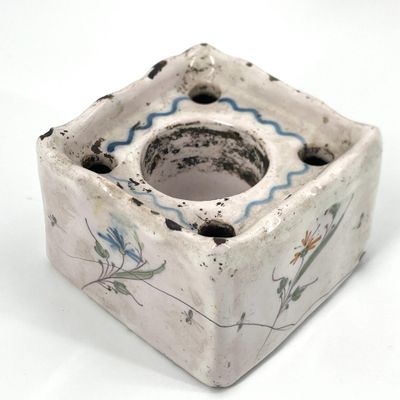 un bougeoir à fleurs blanches et bleues posé sur une surface blanche