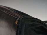 someone is holding a black purse with a brown handle