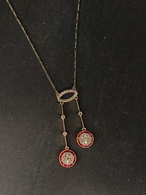 un collier auquel sont suspendues deux pierres rouges et blanches