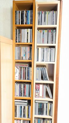 une grande bibliothèque en bois remplie de DVD et de CD