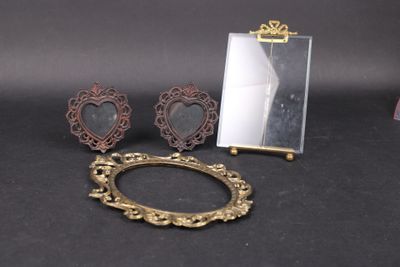 une photo représentant un miroir, un cadre et une paire de boucles d'oreilles posés sur une table