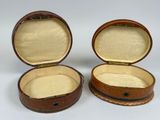 two brown leather boxes with lids are open on a white surface