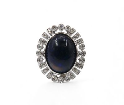 a close up of a ring with a blue stone surrounded by diamonds