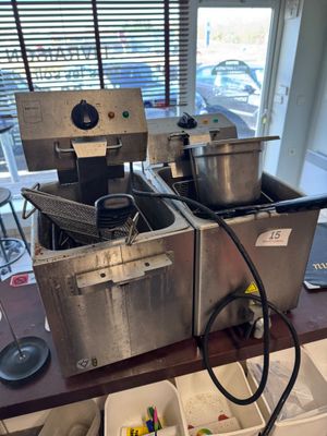 two deep fryers sitting on a table in a kitchen
