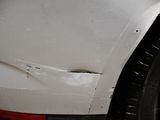 a close up of a white car with a denting on it