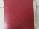 un livre rouge posé sur un sol carrelé blanc
