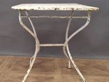an old white iron table with a wooden top on a wooden floor