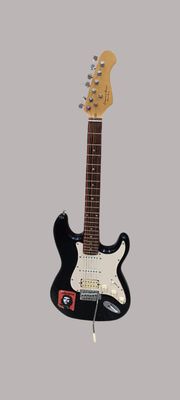 une guitare électrique noire exposée sur un fond gris