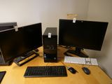 trois écrans d'ordinateur et un clavier posés sur un bureau