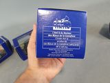 a person holding a blue box of toothpaste on a table