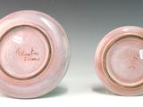 pair of pink glazed plates with writing on them on a white surface