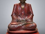 a wooden buddha statue sitting on top of a red box