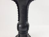 un vase noir posé sur une surface blanche