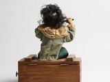 a small doll sitting on top of a wooden box