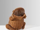 un petit panier en osier muni d'une anse, posé sur une surface blanche