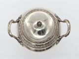 an antique silver plate with a lid on a white surface