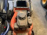 two lawn mowers and a mower cart in a garage