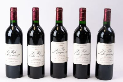 quatre bouteilles de vin rouge sont alignées sur une surface blanche