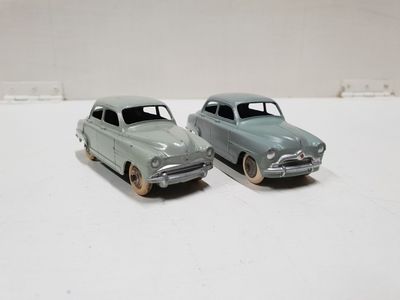two toy cars sitting side by side on a white surface