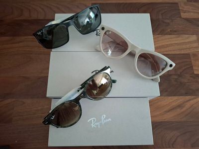 trois paires de lunettes de soleil posées sur une boîte, sur un plancher en bois