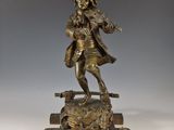 une statue antique en bronze représentant un homme jouant du violon
