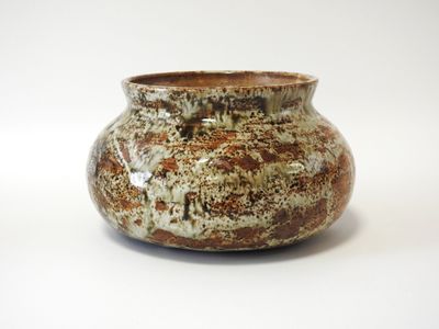 un vase brun et blanc posé sur une surface blanche