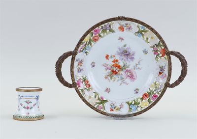 a white plate with a floral design on it next to a small cup
