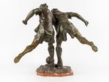 bronze statue of two men kicking a soccer ball on a marble base