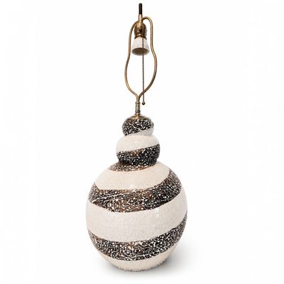 une boule de Noël en verre rayée de blanc et de noir, surmontée d'une clochette