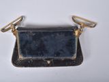 a small black purse with a gold handle on a white surface