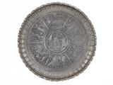 une plaque d'argent ornée d'un motif sur une surface blanche