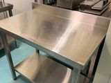 une table en acier inoxydable dans une cuisine, sur laquelle est posé un mixeur