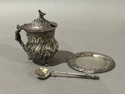 une théière en argent et une assiette en argent sur laquelle repose une cuillère